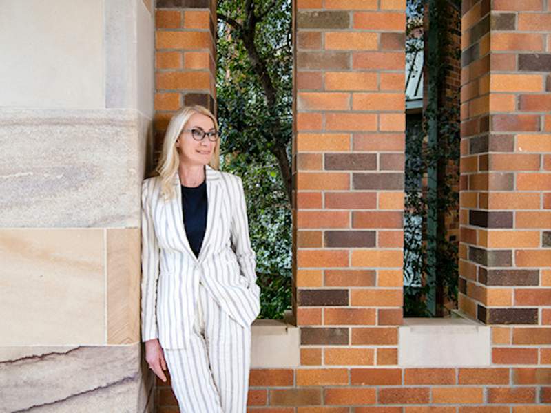 Rose Alwyn warden of St Johns College in a white suit in front of a building
